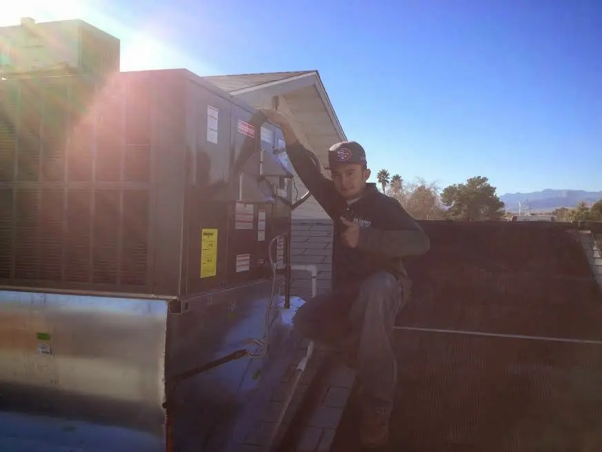 HVAC technician performing AC Tune-Up on a rooftop unit in Mandeville
