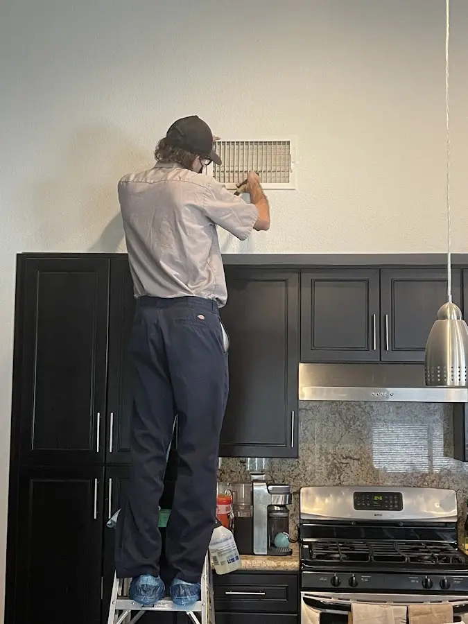 Technician inspecting an air vent during HVAC service in Mandeville